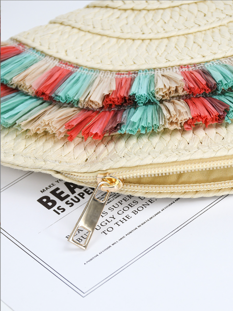 Pochette d’été rétro en paille naturelle, forme demi-lune, avec détails colorés corail et turquoise, format 33x16,5 cm, portée à la main